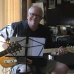 Smiling musician playing guitar indoors.