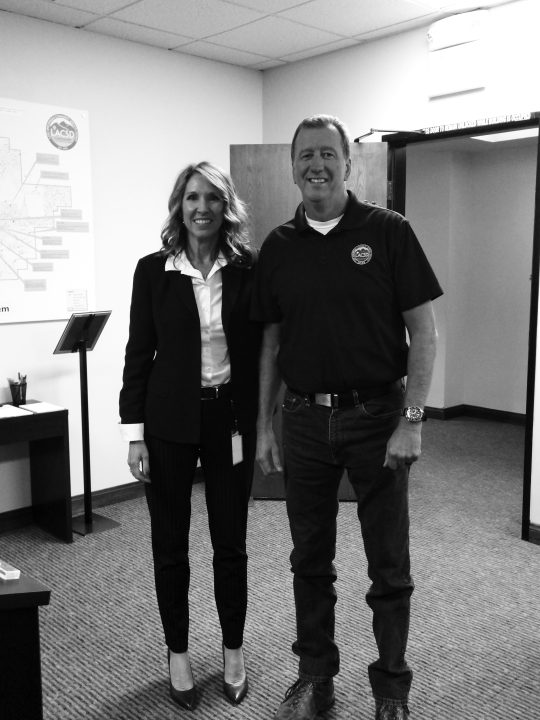 Two people smiling in an office setting.