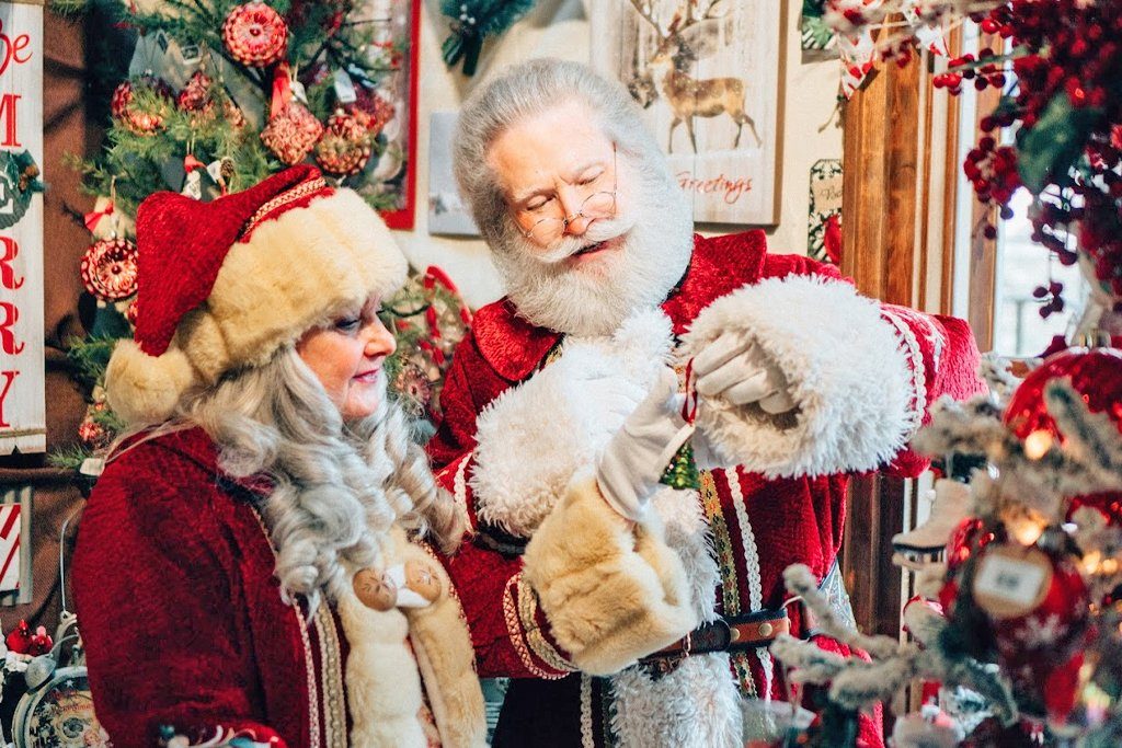 Santa and Mrs. Claus decorating a Christmas tree.
