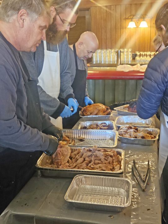 Volunteers preparing holiday meal in kitchen.