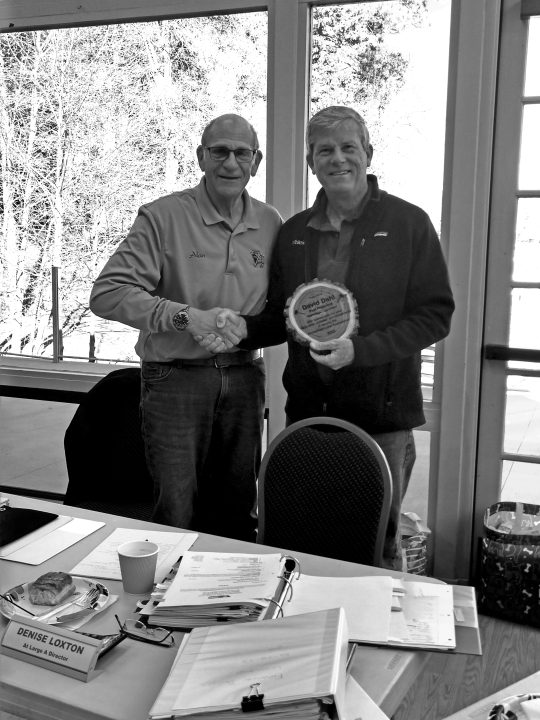 Two men shaking hands, one holding plaque.