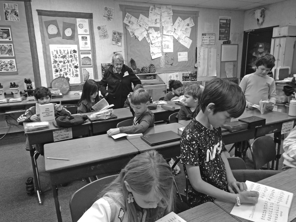 Students reading in a classroom with a teacher.