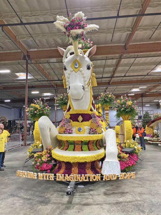 Colorful parade float with floral unicorn design.