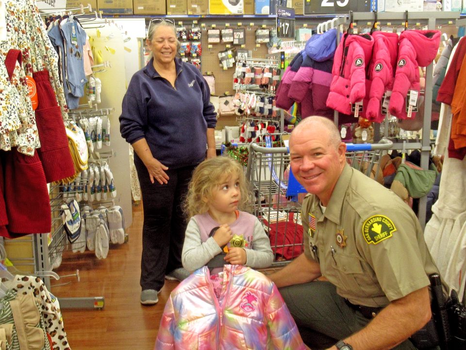 Smiling police officer with child in store.