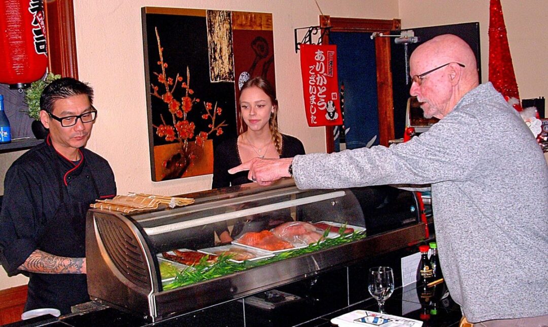 Chef and customers at sushi restaurant counter