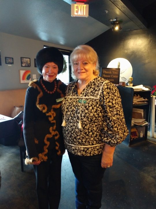Two women posing together in a cozy room.