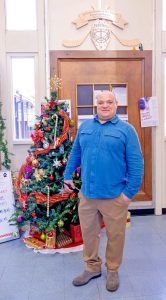 Terry Gomes poses for a photograph by the school's festive holiday tree.