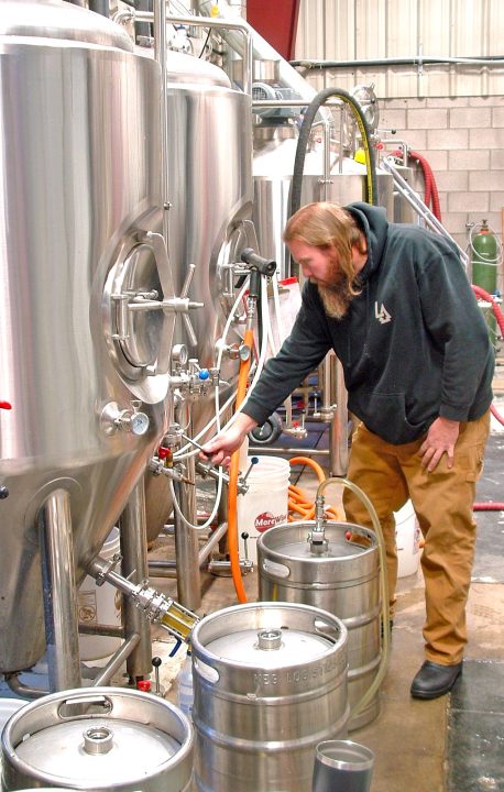 Master brewer Rich Shaltz, who taught the art at Cal State, Pomona, makes expert adjustments along one row of stainless-steel tanks at the brewery.