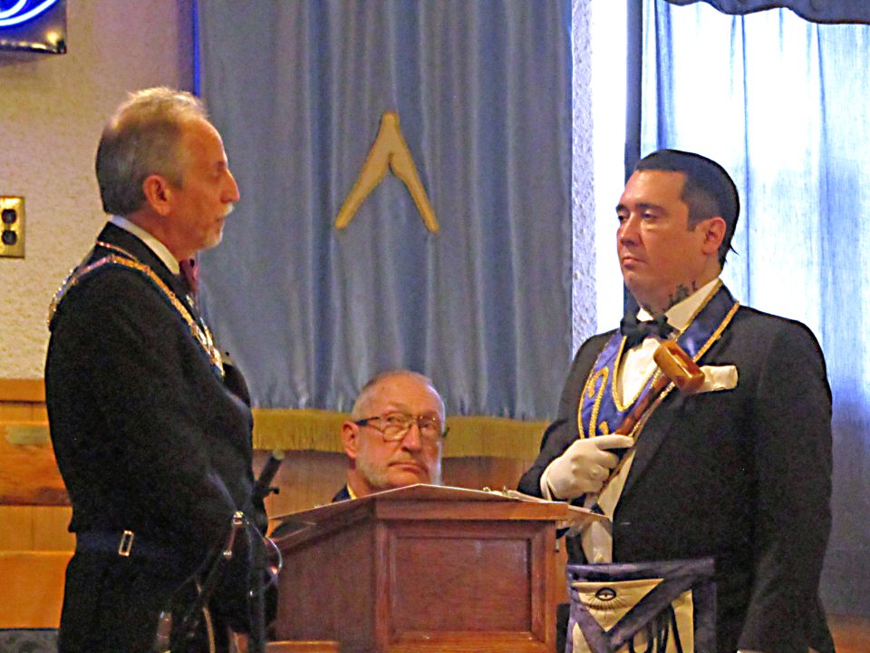 Installing officer Russ Charvonia, PGM has handed the gavel of his office to new Worshipful Master Johnny Royal at the recent Masonic installation of officers with the Chaplain Clint Waugh, in the center, looking on.