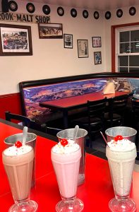 Fountain-style malts and shakes come in numerous varieties. In the background, classic-car images decorate the booths, while vintage artwork and 45-rpm records hang on the walls. (Photo courtesy of Cedar Glen Malt Shop)