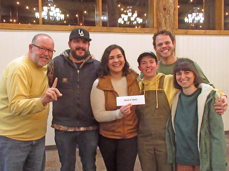 Group of six people smiling indoors.