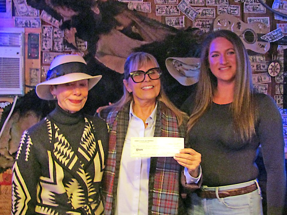 Three women posing with a donation check