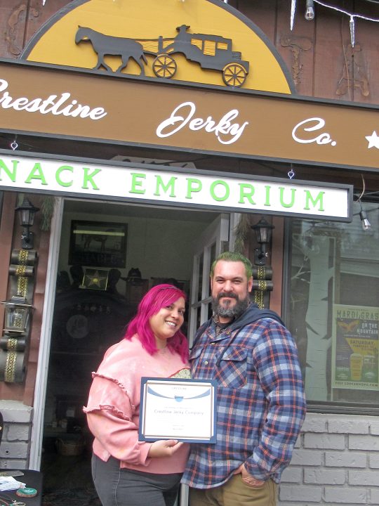 Travis Pasternostro and partner Cynthia Durousseau, of Crestline Jerky Co. and Snack Emporium, holding their grand opening certificate at last weekend’s block party on Lake Drive in Crestline.