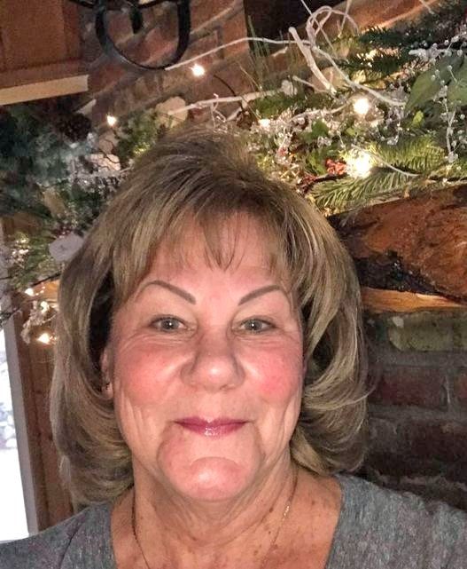 Smiling woman with holiday decorations behind her.