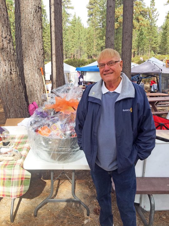 Smiling man beside decorated gift basket outdoors.