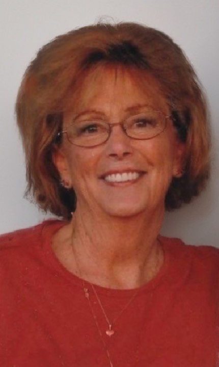 Smiling woman with glasses wearing red shirt.