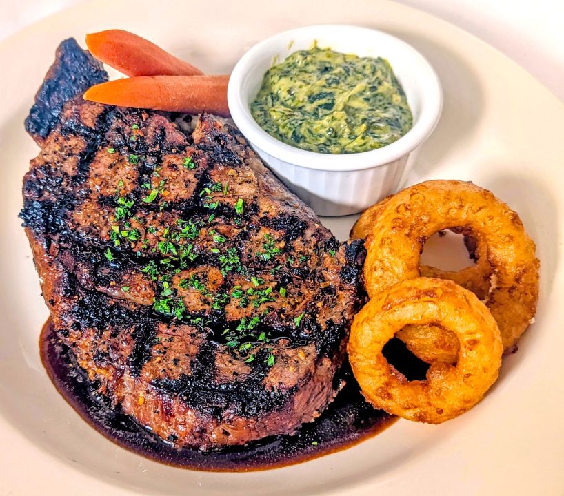 The 12-ounce ribeye steak is accompanied by onions rings and creamed spinach. (Photo courtesy of Diane’s Saddleback Grill)