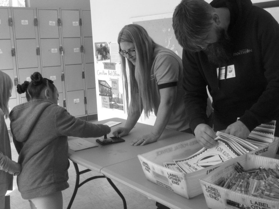 Students hand-canceling a letter during their field trip to the VOE post office.