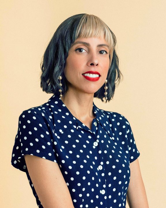 Smiling person in polka dot blouse with short hair.