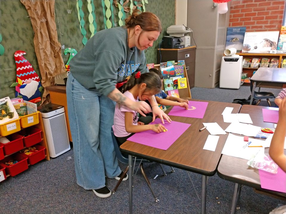 Teacher helping students with classroom activity.