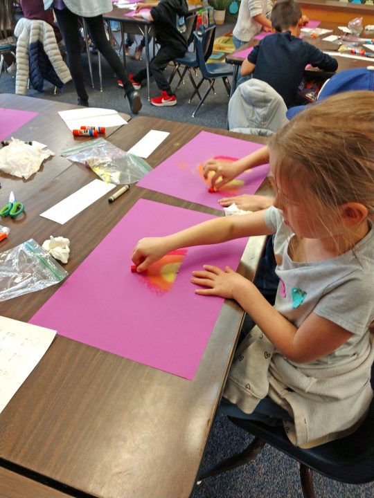 Using the side of the chalk, the students created rainbows to begin their art project.