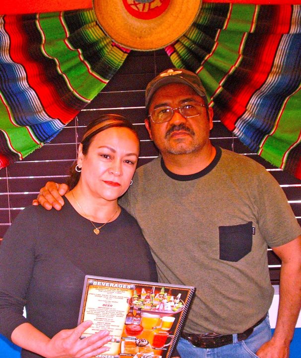 Couple holding menu under colorful Mexican decor