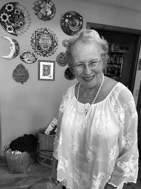 Smiling woman in kitchen with decorative wall art.