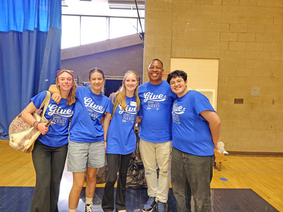 Group of volunteers in blue shirts smiling together.
