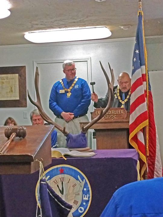 Ceremony with officials and American flag indoors.