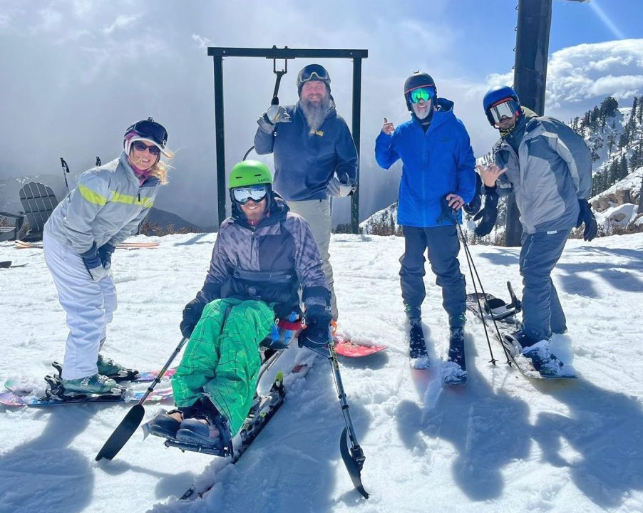 Group of skiers posing on snowy mountain slope.