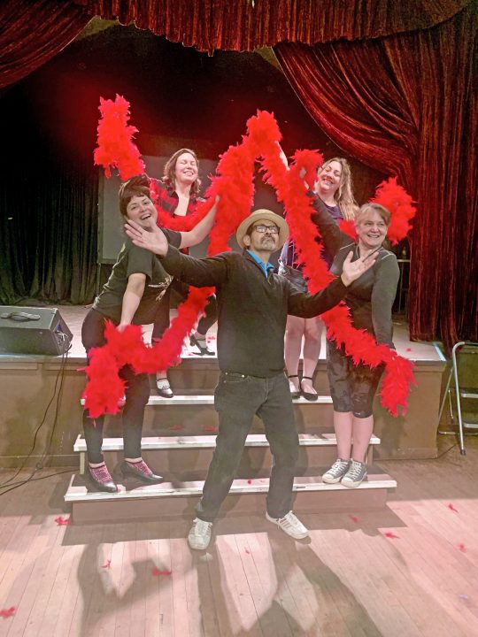 Group with red feather boas on stage
