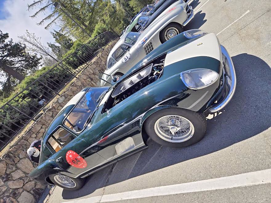 Vintage sports cars parked outdoors, scenic backdrop.