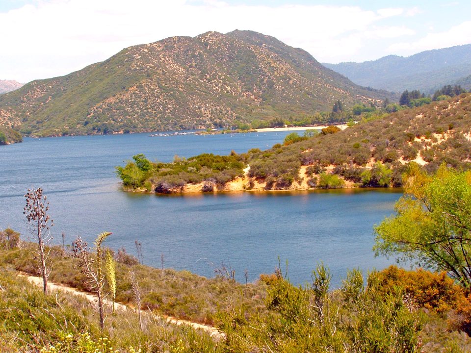 Scenic lake surrounded by hills and greenery.