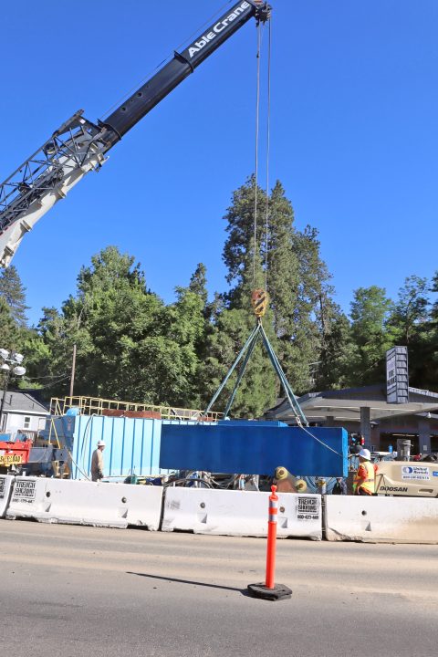The repaired concrete electrical vault is lowered into a subterranean cavern adjacent to Snyder’s Tire Works on Lake Drive.