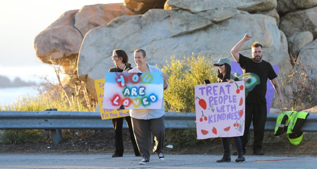 People holding signs promoting kindness and love.