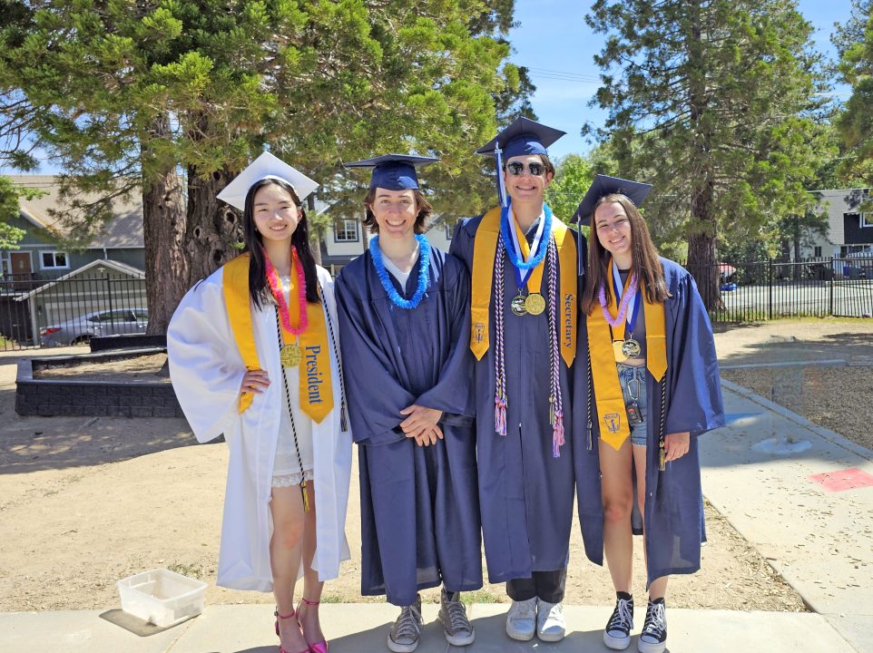 Group of graduates in caps and gowns outdoors.