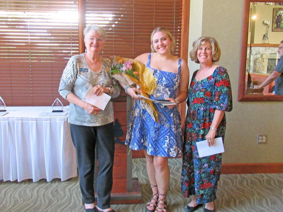 Three women posing with flowers and cards.
