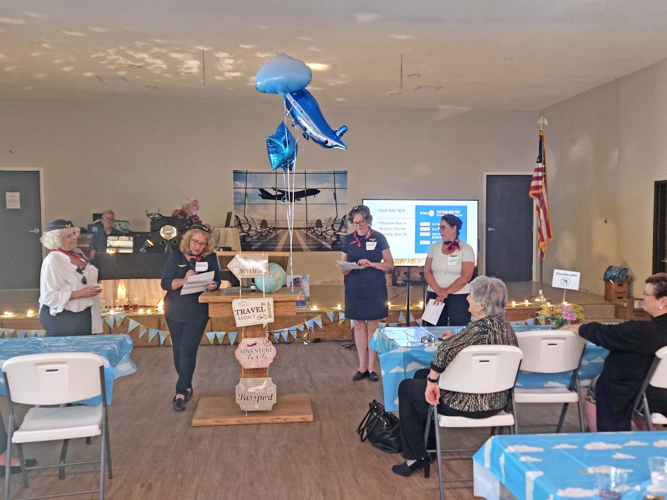 The flight attendants – Laura Dyberg, Michelle French, Elizabeth O’Neil and Jenny Hueter – gave instructions to the passengers, including President Mary Ann Dickinson and District Governor Jamie Zinn (seated). (Photo by Mary-Justine Lanyon)