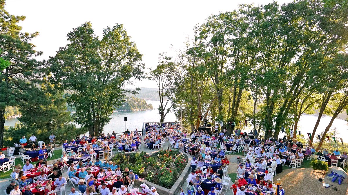 Outdoor event by lake with many attendees.