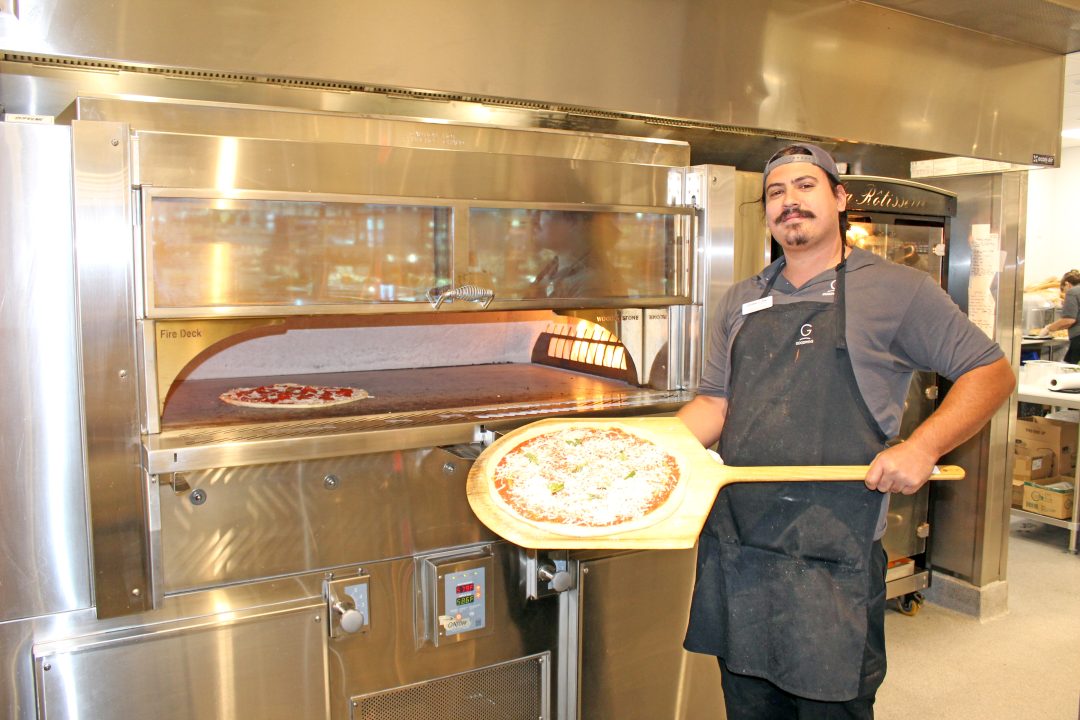 Chef preparing pizza in restaurant kitchen.