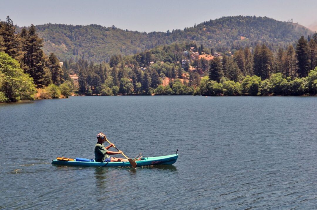 Person kayaking on a scenic lake with mountains.