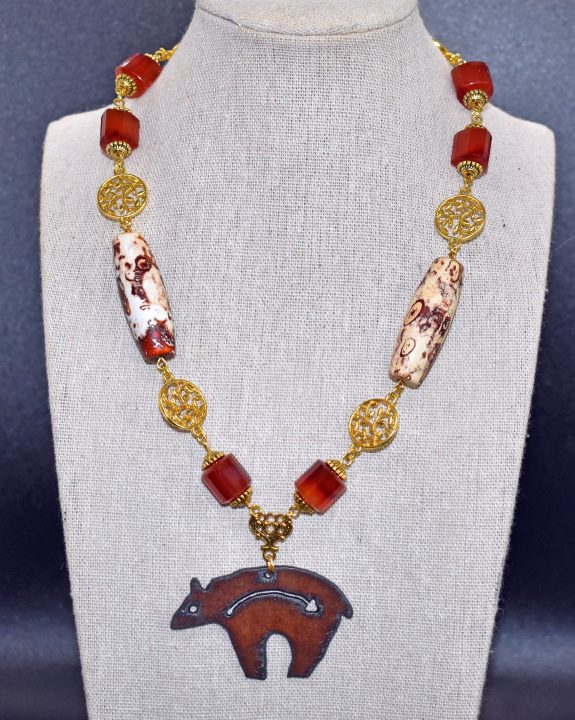 The principal element of a necklace incorporating carnelian and ceramic beads is a Rusty Bear pendant. (Bloduewedd photo and jewelry image by L. Cook)