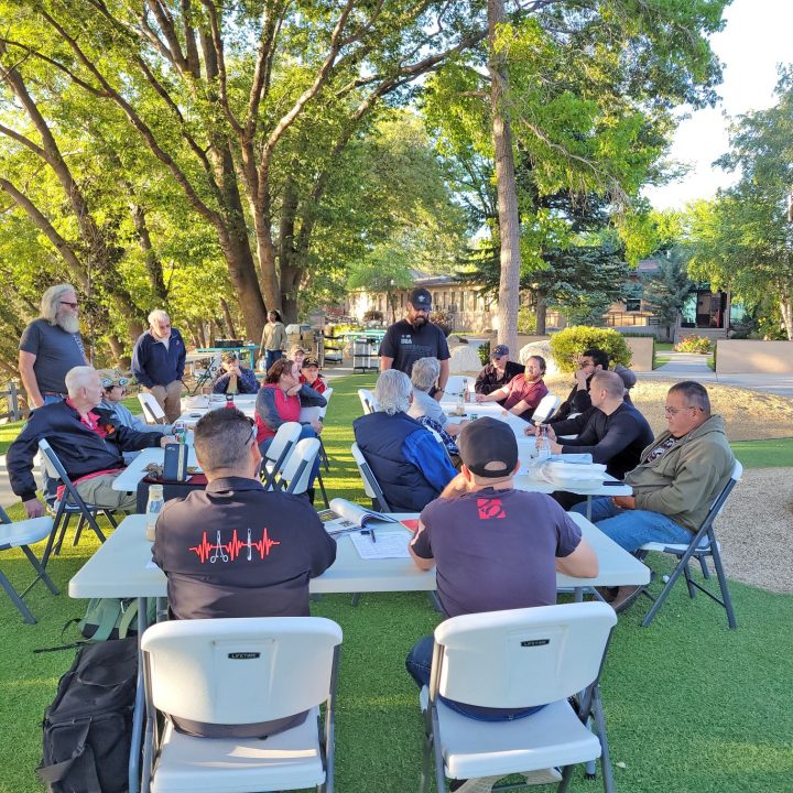 Outdoor meeting with people seated at tables.