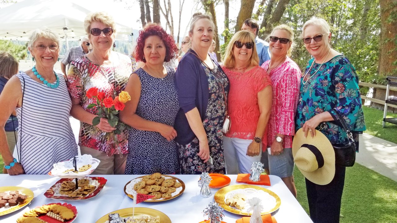 Group of women posing at outdoor gathering with food.