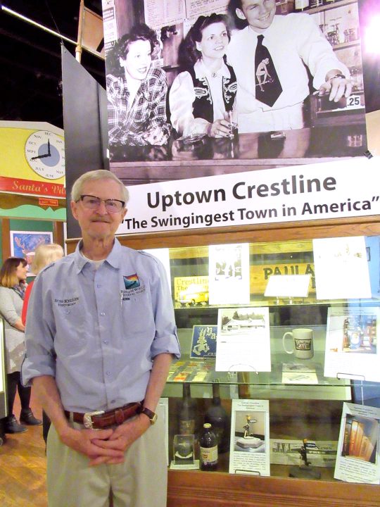 Man standing by Crestline history display, museum exhibit.