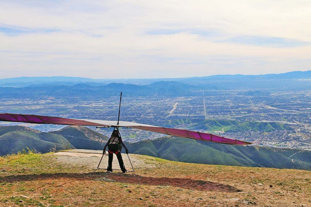 Hang glider preparing to launch over scenic valley.