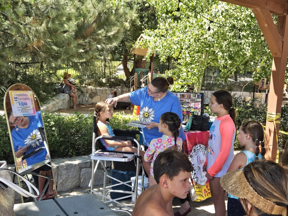 Children lined up to have their faces painted by Julie Price of Oopsie Daisy.