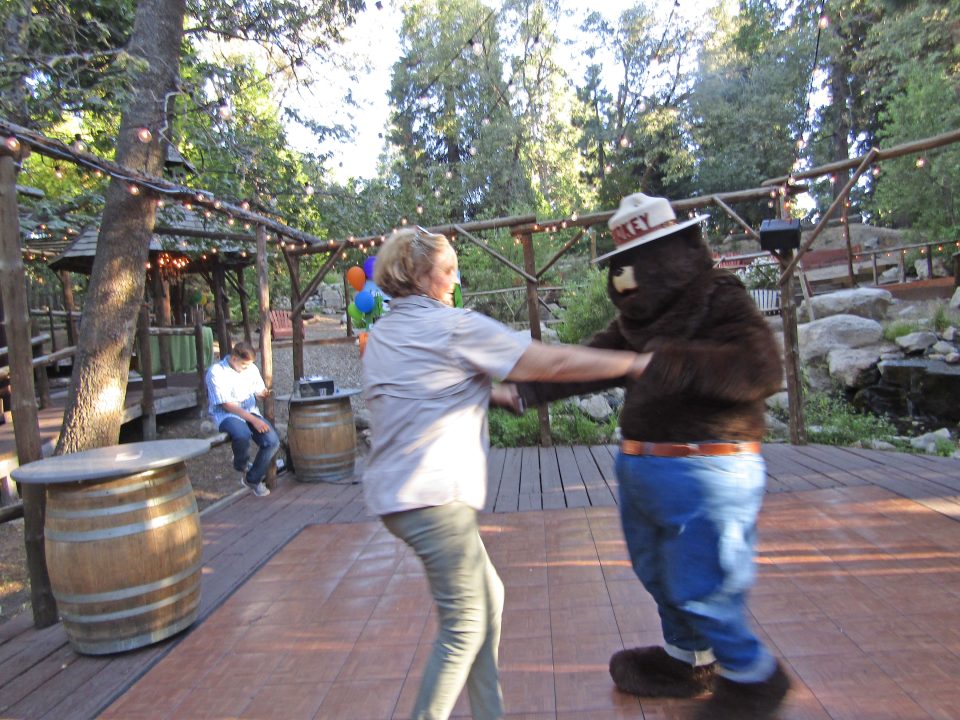 Pine Rose Cabins owner Trish Dufour dances with Smokey Bear.