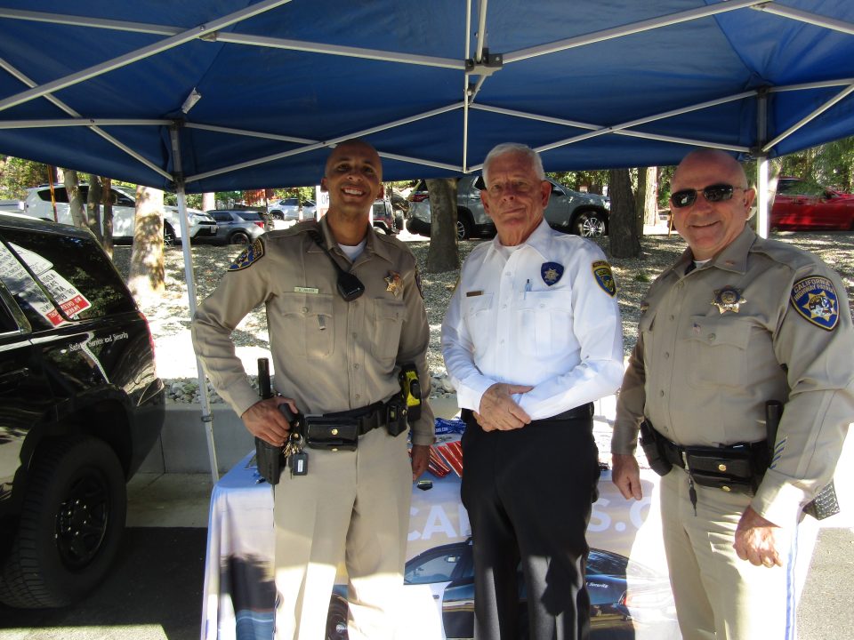 Police officers posing under tent at event.