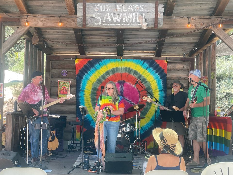 Adrianne, Lisa, Julia, Melissa and Adrianna from Glendora and Orange County enjoyed last year’s Brewfest at Tavern Bay Beach Club so much they couldn’t resist attending this year’s event. (Photos by Douglas W. Motley) Band performing at outdoor venue with tie-dye backdrop.
